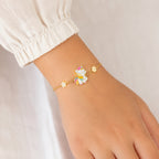 A delicate gold chain bracelet with a colorful pastel unicorn charm and star accents, shown worn on a person's wrist.