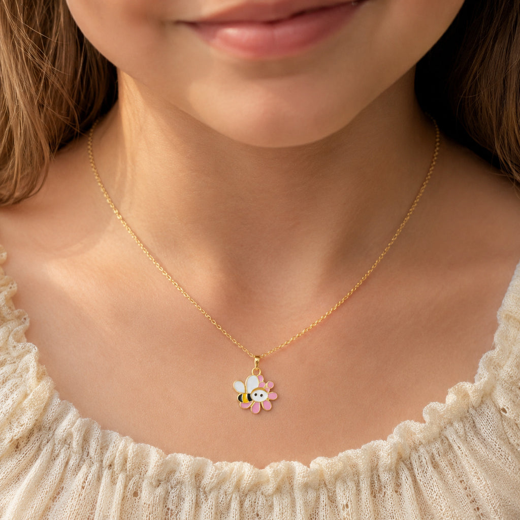 Child wearing a gold bee and pink flower pendant on a fine chain