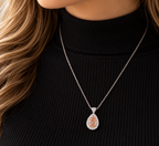 Elegant peach pink teardrop gemstone necklace with sparkling white halo stones, styled on a black outfit – La Noosha Jewelry