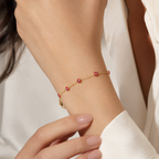 14K gold red evil eye bracelet worn on model wrist, delicate yellow gold chain with red enamel charms for protection and everyday luxury style