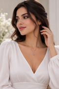 Elegant woman wearing a delicate pear-shaped gemstone halo pendant necklace with sparkling accent stones and a fine chain, styled with a V-neck blouse.