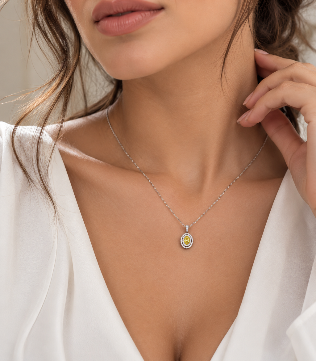 Woman wearing a delicate 14K white gold oval gemstone pendant necklace with a sparkling double halo setting, styled with an elegant white V-neck blouse.