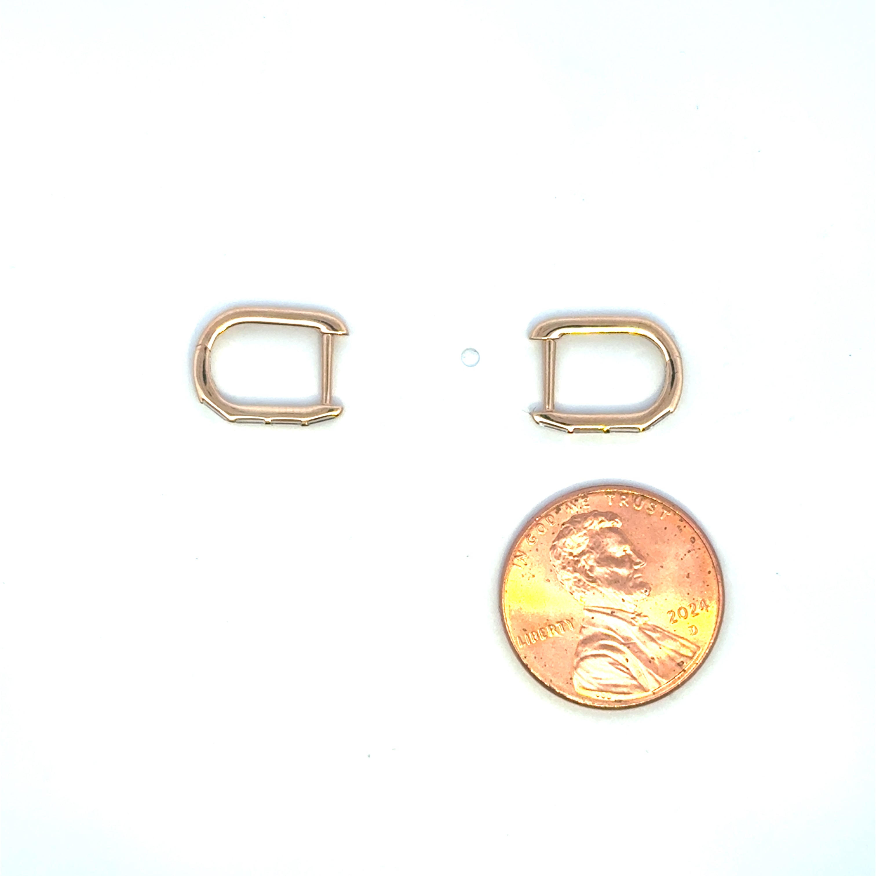 18K yellow gold baguette diamond huggie earrings shown beside a US penny for size reference