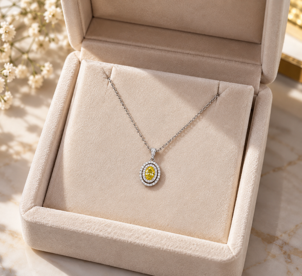 Delicate 14K white gold necklace featuring a yellow oval-cut gemstone surrounded by a sparkling double halo, displayed in an elegant ivory velvet jewelry gift box.