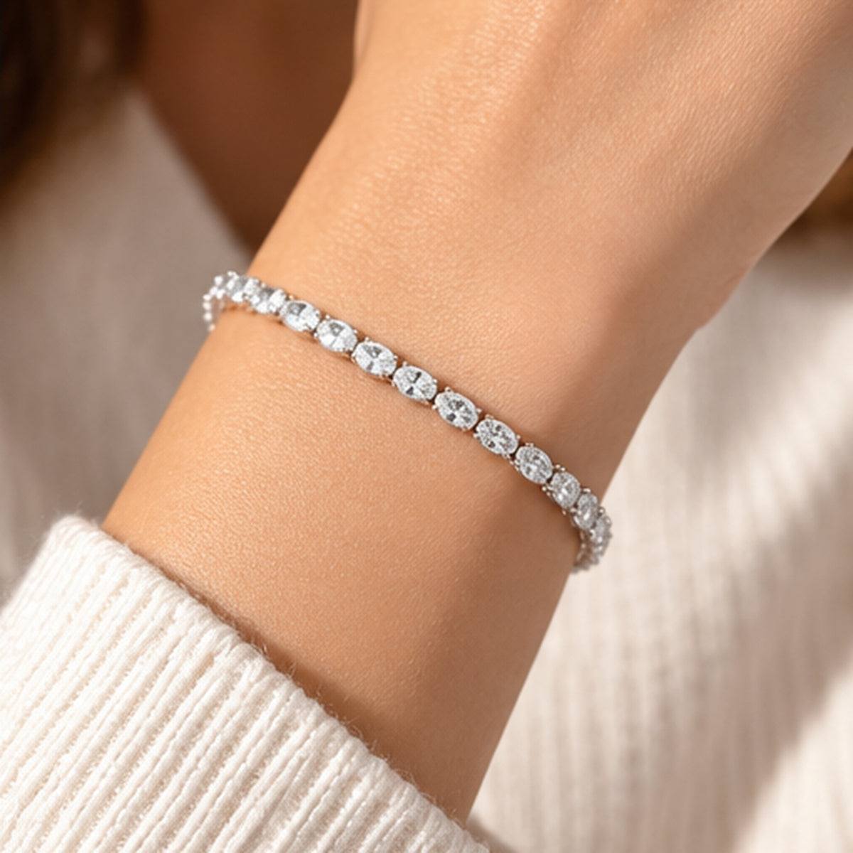 Delicate East-West oval diamond tennis bracelet with sparkling horizontally set stones styled with a cream sweater.