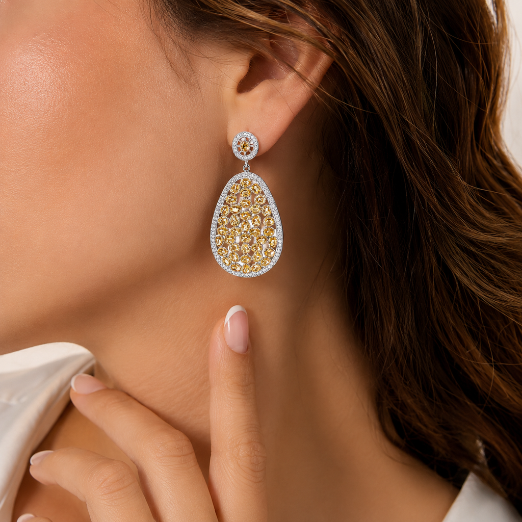 Luxury sterling silver teardrop statement earrings featuring champagne-colored gemstones and sparkling cubic zirconia accents, elegantly worn by a woman in a close-up lifestyle portrait.