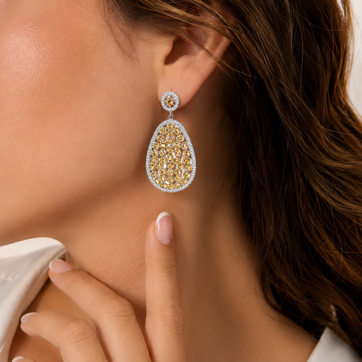 Luxury sterling silver teardrop statement earrings featuring champagne-colored gemstones and sparkling cubic zirconia accents, elegantly worn by a woman in a close-up lifestyle portrait.