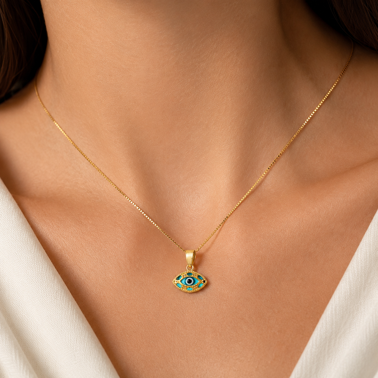 Model wearing a 14K gold evil eye necklace with blue eye pendant on a delicate box chain.