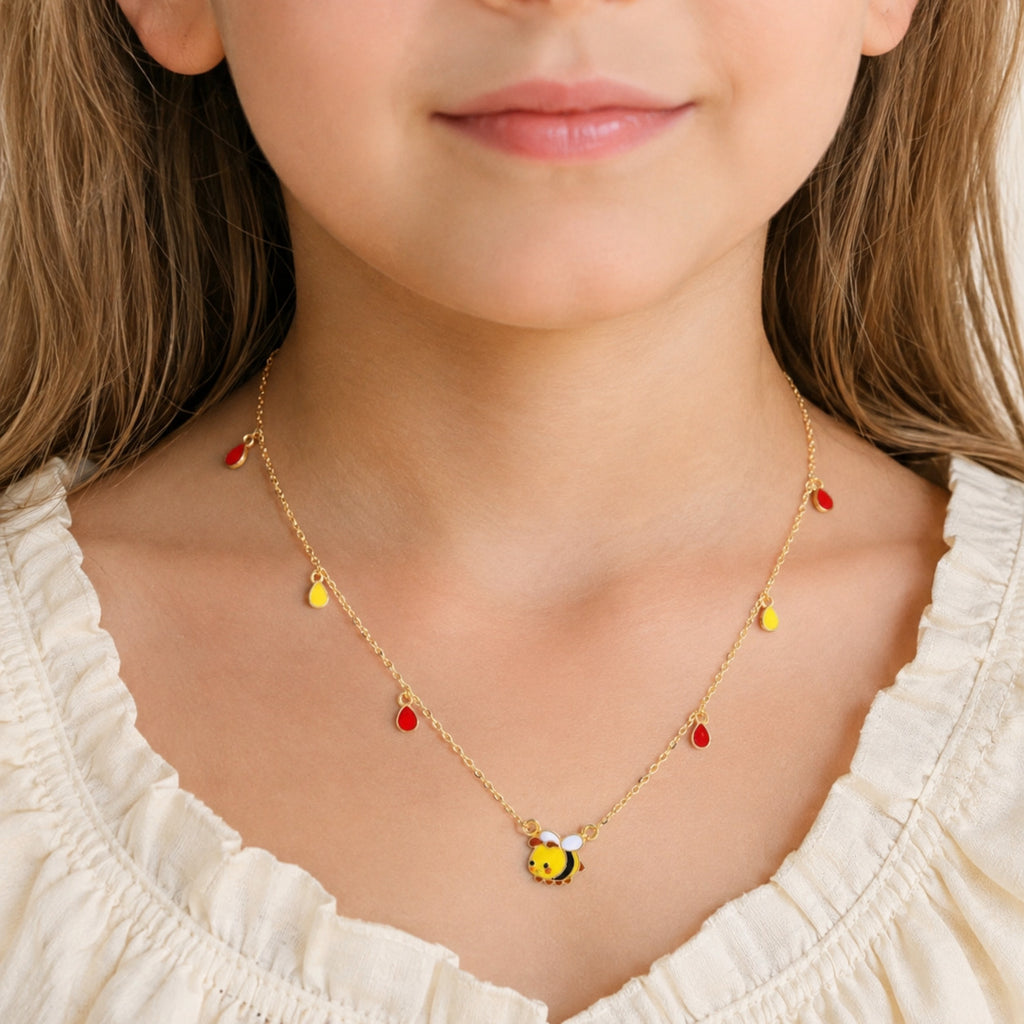 Child wearing a gold bee necklace with red and yellow teardrop charms