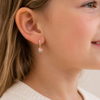 Child wearing a gold drop earring with clear stones and a colorful cupcake charm