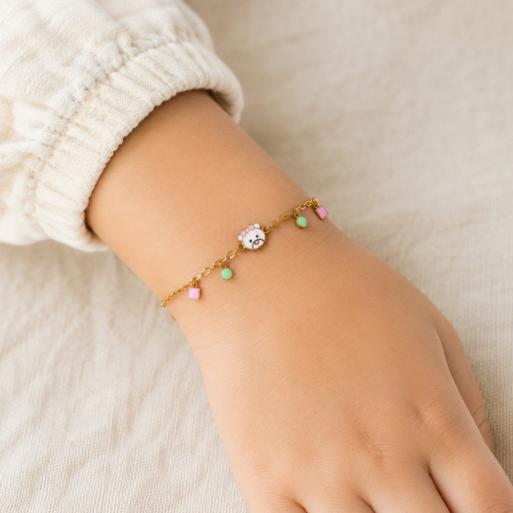 Child wearing a gold animal face bracelet with pink square and mint circle charms