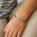 Child wearing a gold helicopter bracelet with small black beads