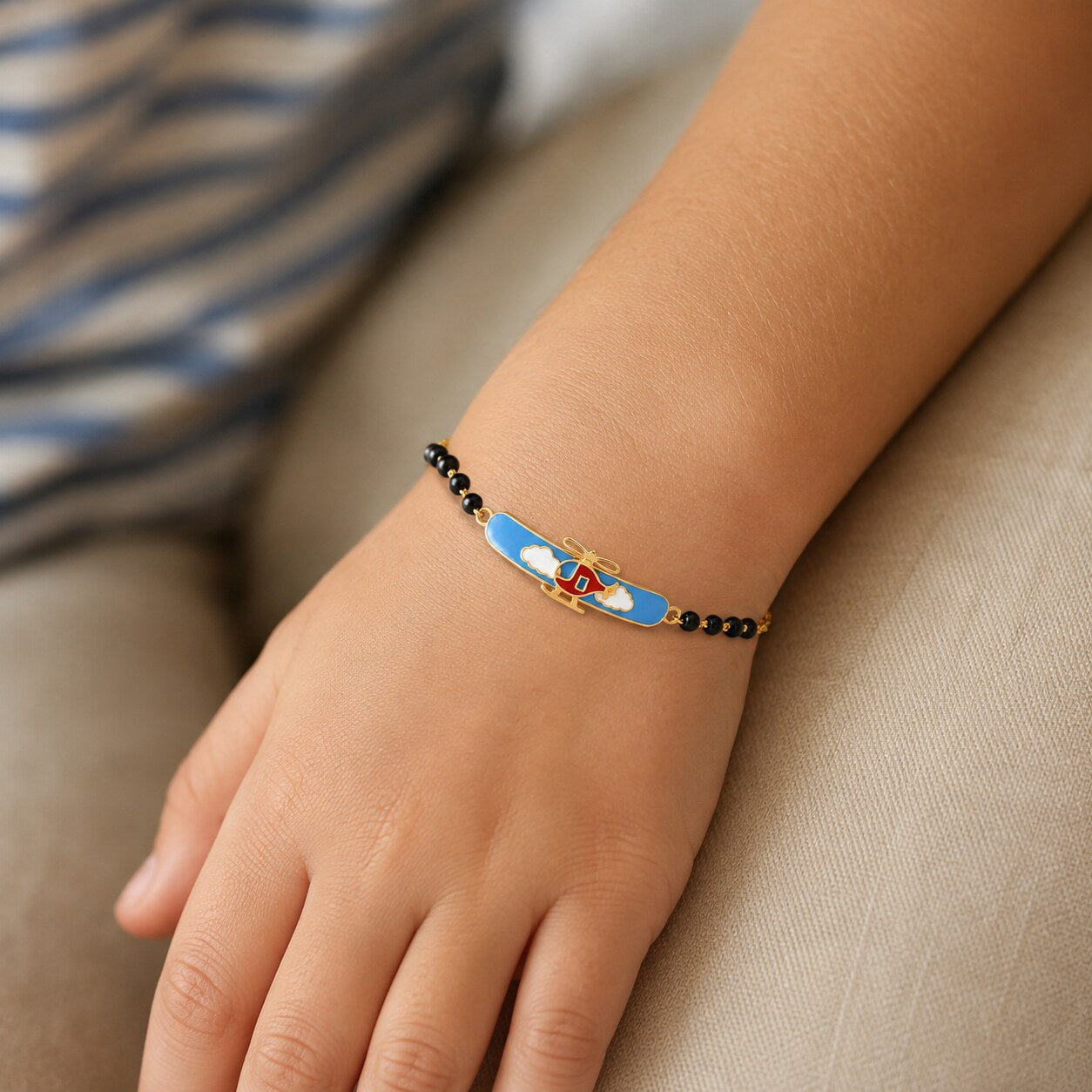 Child wearing a gold helicopter bracelet with small black beads