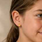 Child wearing a small gold princess dress stud earring