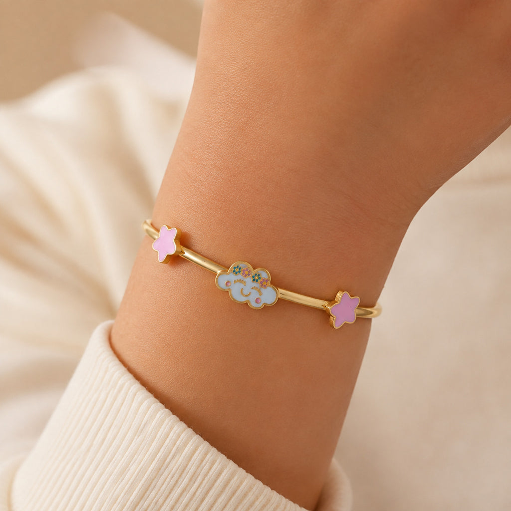 Child wearing a gold bangle with a smiling cloud and pink star accents