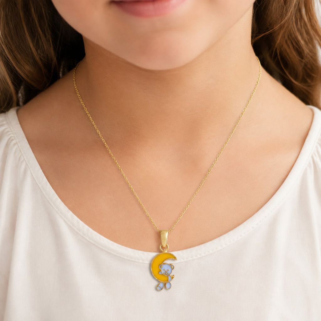 Child wearing a gold teddy bear and yellow crescent moon pendant