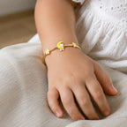 Child wearing a slim gold teddy bear moon and butterfly bangle