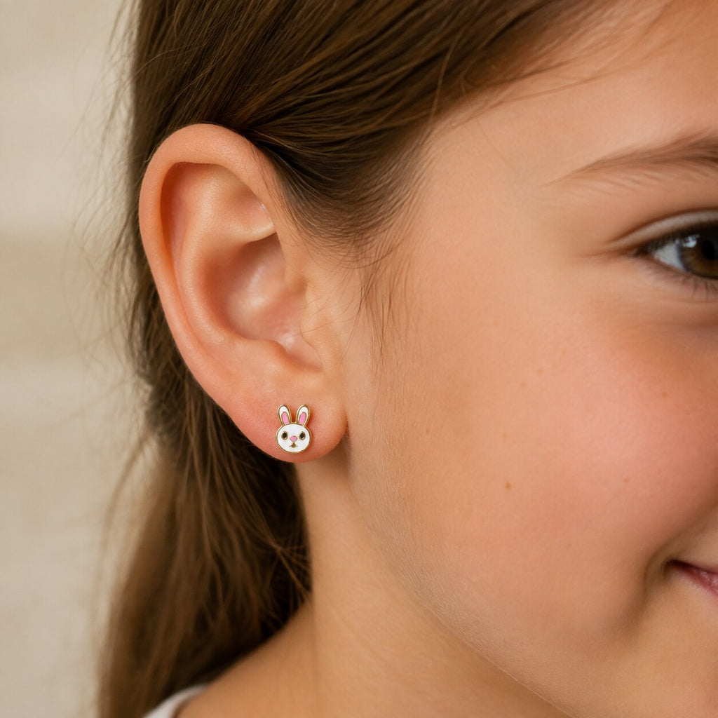 Child wearing a small gold and white bunny-face stud earring