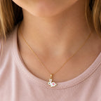 Child wearing a small gold white bunny and pink heart necklace