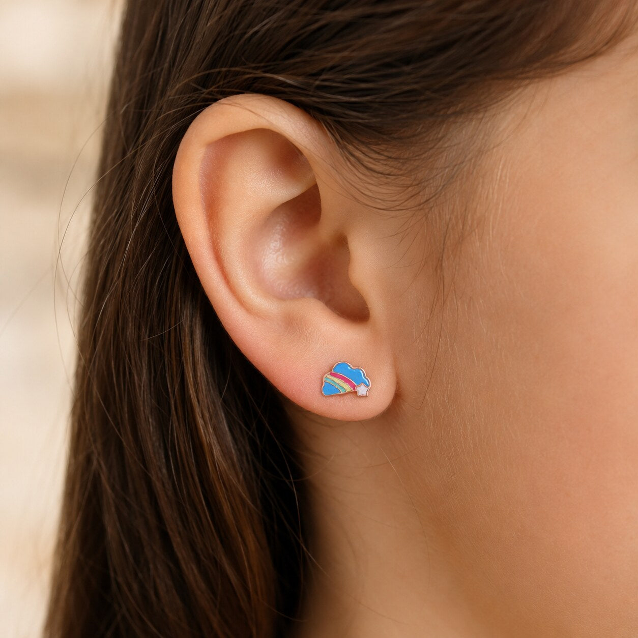 Child wearing a small rose gold rainbow cloud stud earring