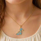 Child wearing a yellow gold necklace with a small colorful dinosaur pendant