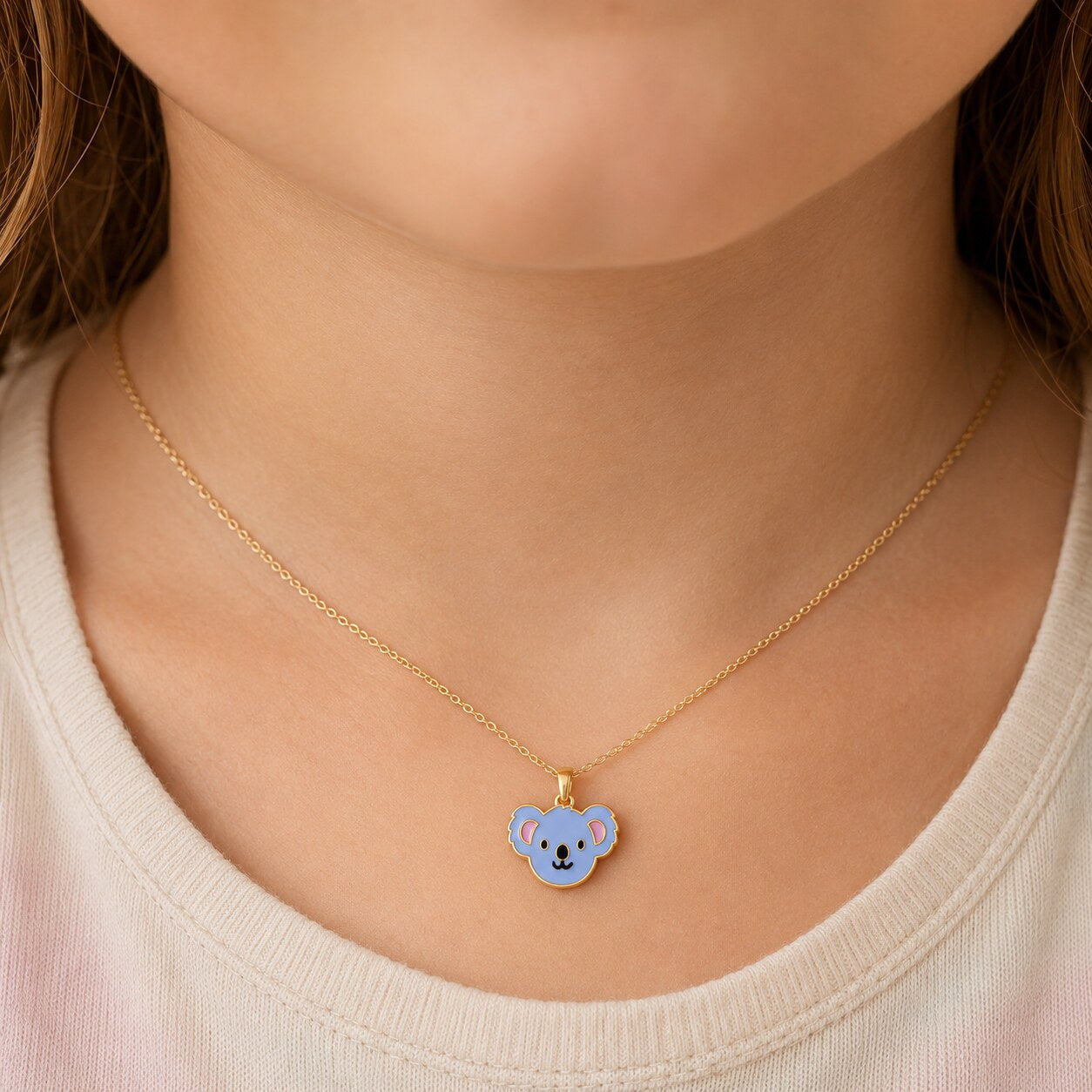 Child wearing a petite 14K yellow gold blue enamel koala pendant