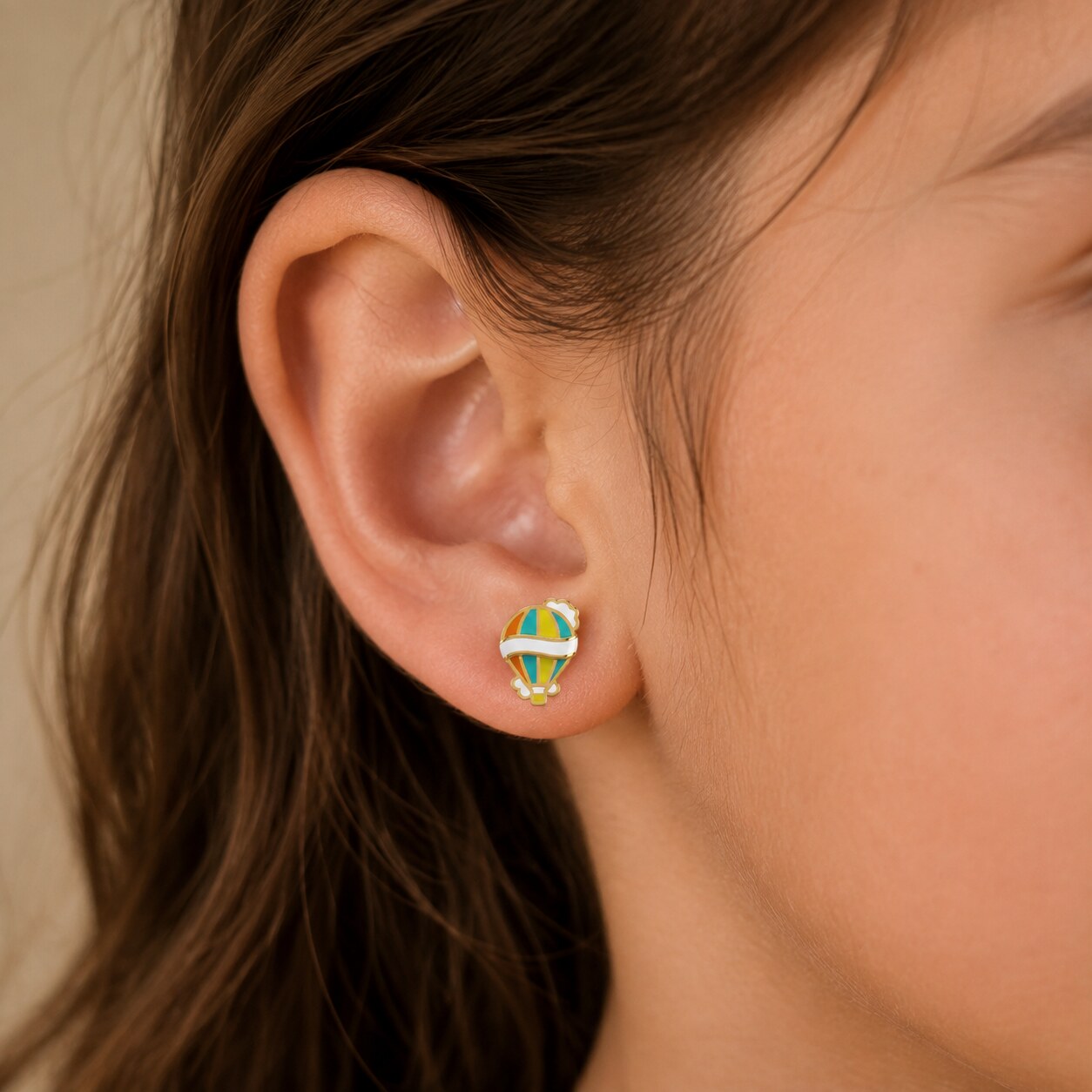 Child wearing a small colorful yellow gold hot air balloon stud earring