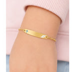 Child wearing a petite yellow gold cross and angel wing ID bracelet