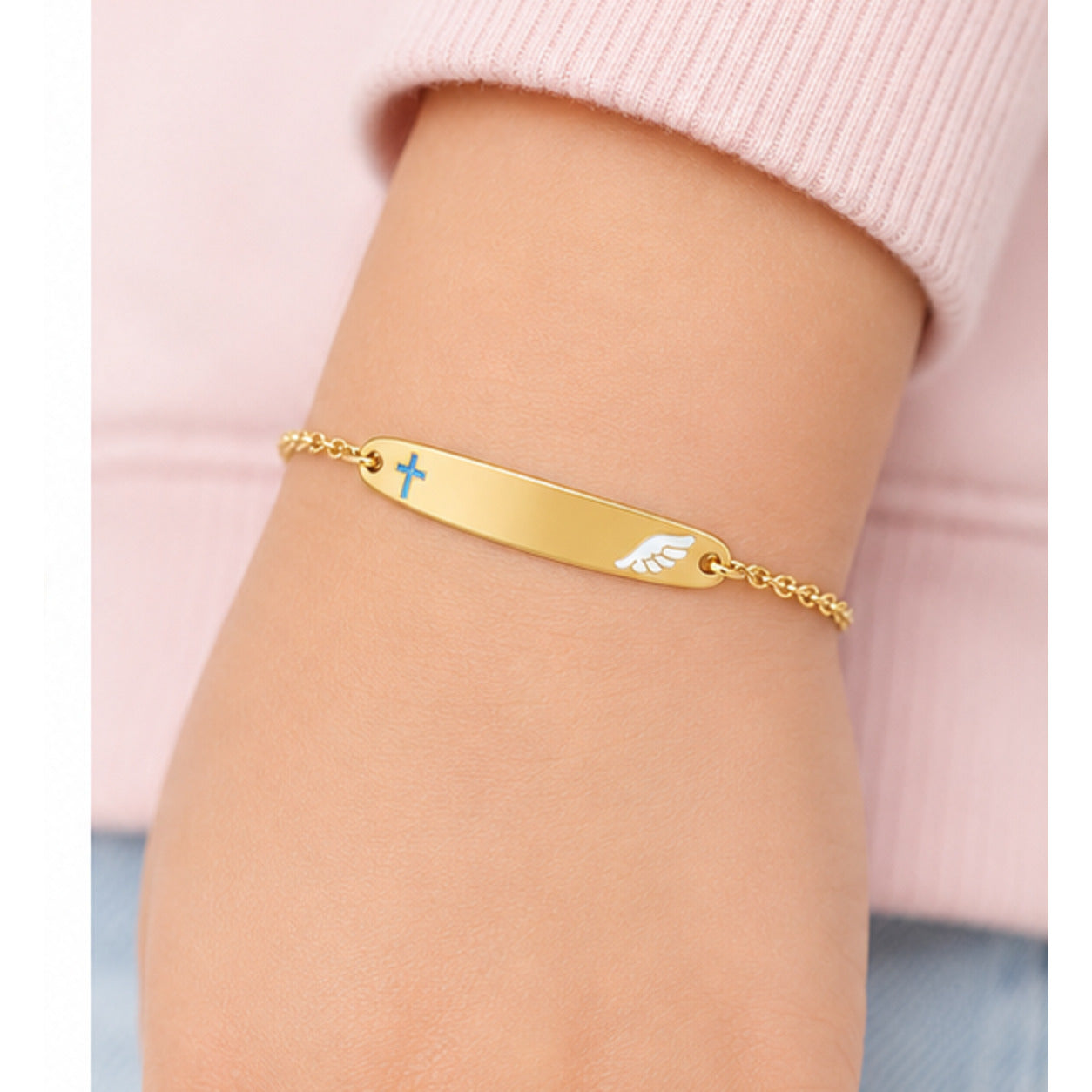 Child wearing a petite yellow gold cross and angel wing ID bracelet