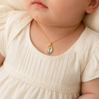 Petite yellow gold guardian angel pendant styled on an infant model