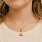 Child wearing a small yellow gold colorful giraffe pendant on a delicate chain