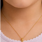 Child wearing a small yellow gold multicolor smiling sun pendant
