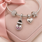 Delicate baby shoe charm with pink and clear sparkling stones, beautifully designed for charm bracelets and a thoughtful newborn gift.